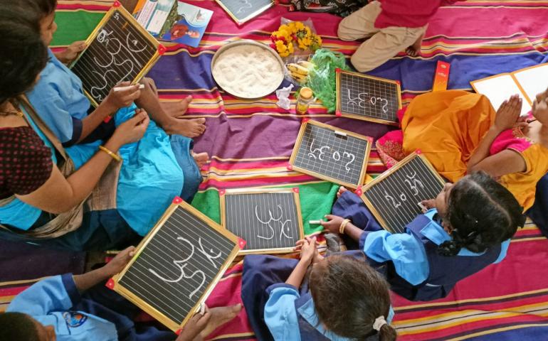 Students writing OMKARA on the Slate 